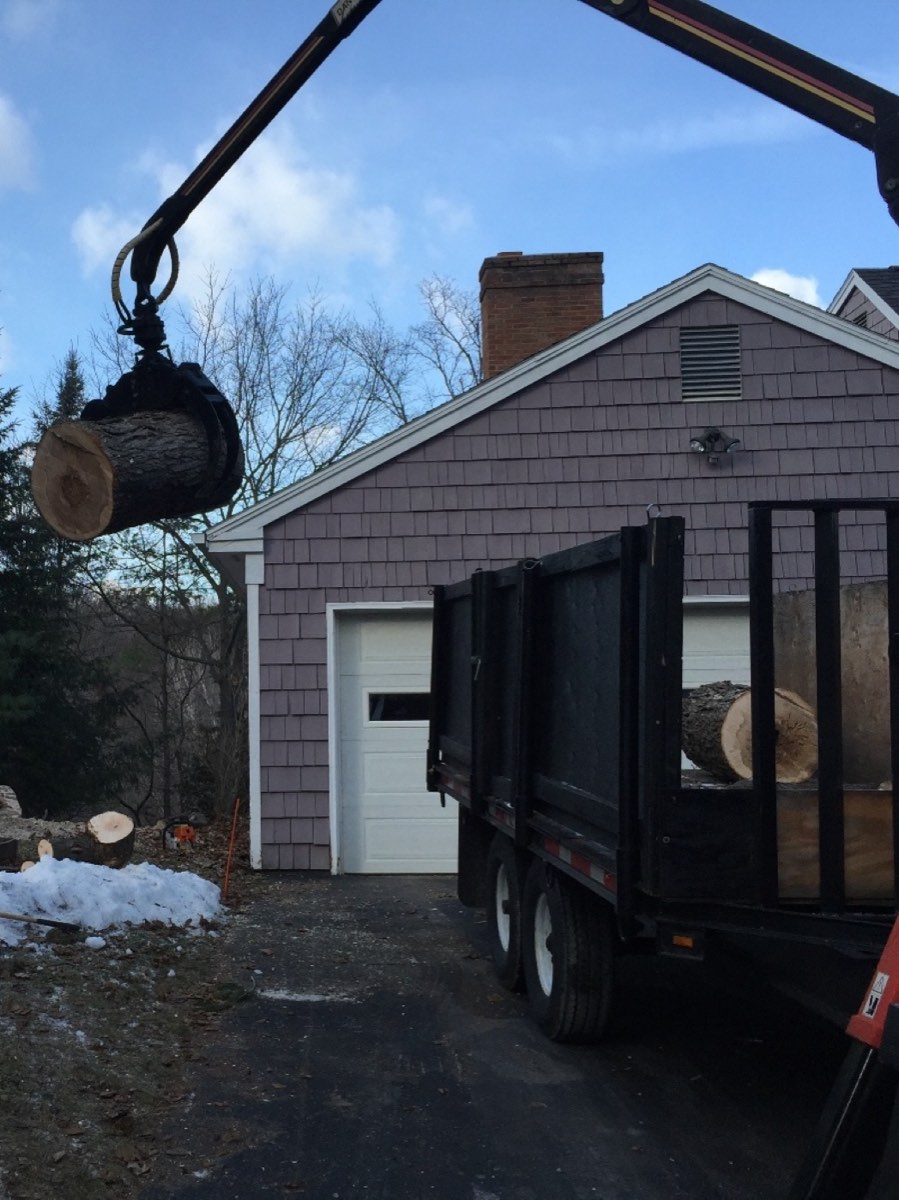 Grapple loading a log round onto the truck on a winter day