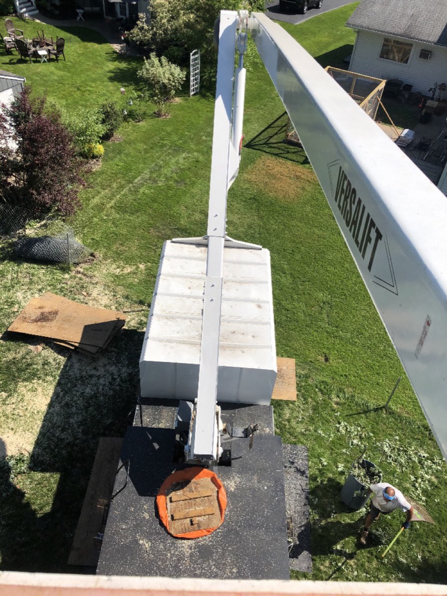 Looking down the Versalift boom as a crew member rakes the yard below